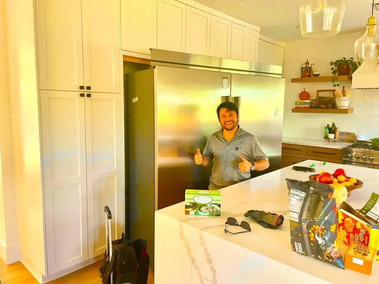 A to Z technician next to a stainless steel refrigerator in a kitchen