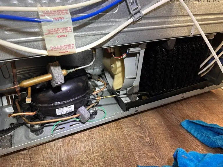 Compressor and tubing at the back of a refrigerator during a repair