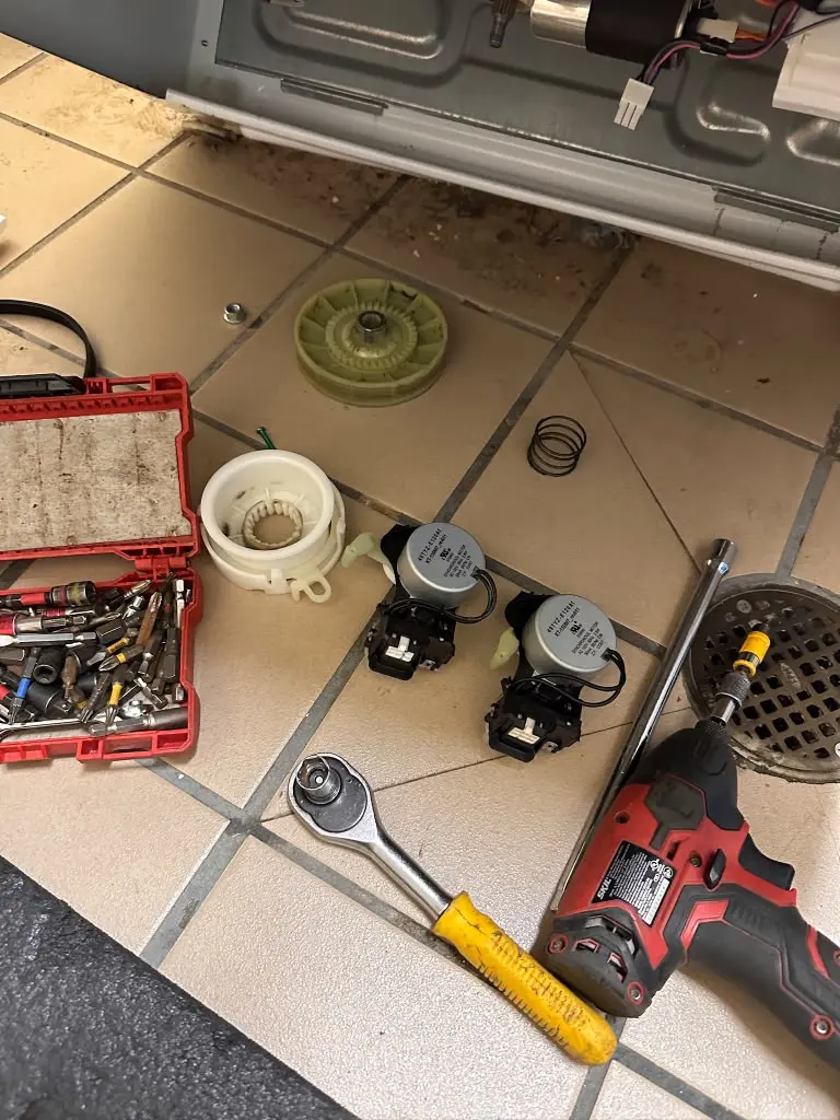 Faq: Tools and removed appliance parts laid out on the floor during a repair