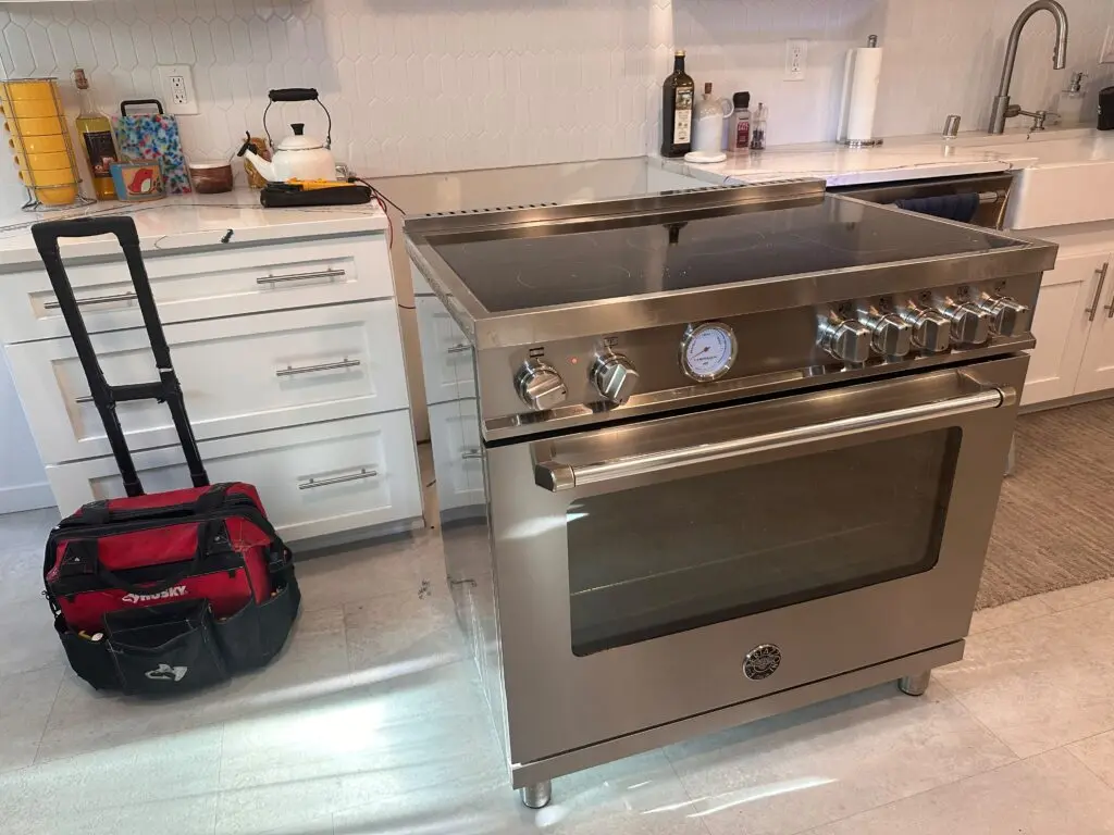 Stainless steel range in a kitchen with the technician tool bag beside it